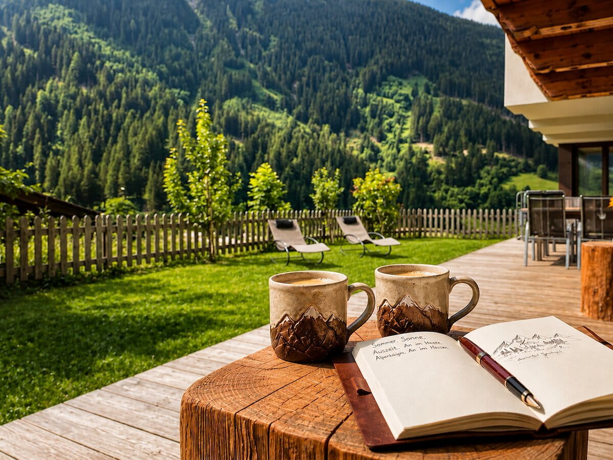 Terrasse der Ferienwohnung Gletscherglühen mit Bergkaffee, Notizbuch und sommerlichem Waldblick